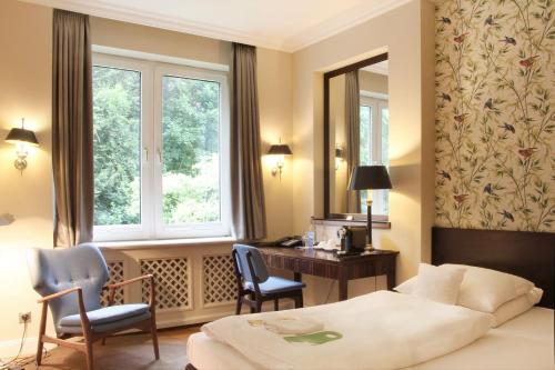 a bedroom with a bed and a desk and a window at Romantik Hotel Kieler Kaufmann in Kiel