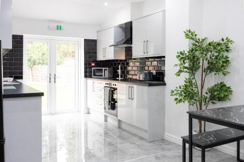a kitchen with white cabinets and black appliances at The Kent- Luxury Rooms in Manchester
