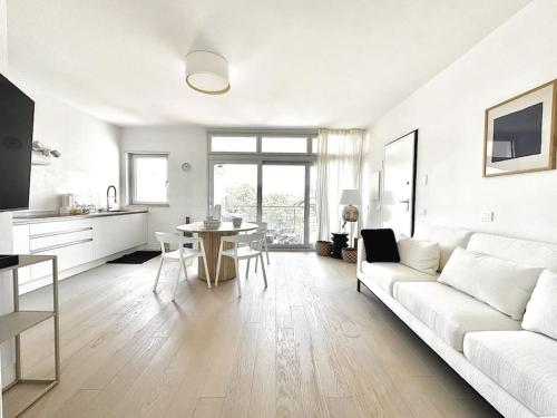 a white living room with a white couch and a table at Aptments4 - real estate solutions in Olbia