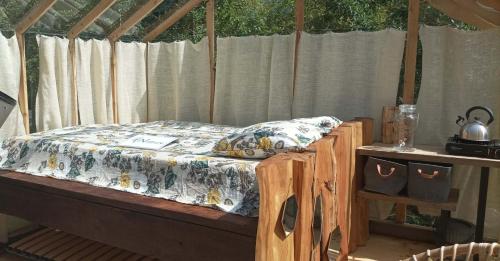 un lit dans une tente avec un cadre de lit en bois dans l'établissement Insolite Cabane du Rêveur, à Pagny-sur-Moselle