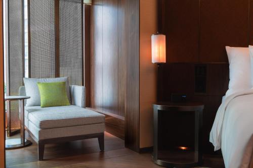 a bedroom with a chair and a bed and a fireplace at Grand Hyatt Singapore in Singapore