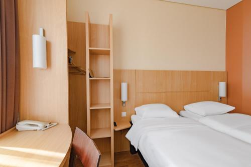 two beds in a room with a table and chairs at Ibis Kaunas Centre in Kaunas