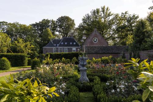 a garden with flowers and a house in the background at Landgoed Huis te Jaarsveld in Jaarsveld