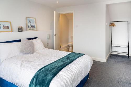 a bedroom with a white bed with a green blanket on it at The Lookout, Seaside Getaway in Cleveleys
