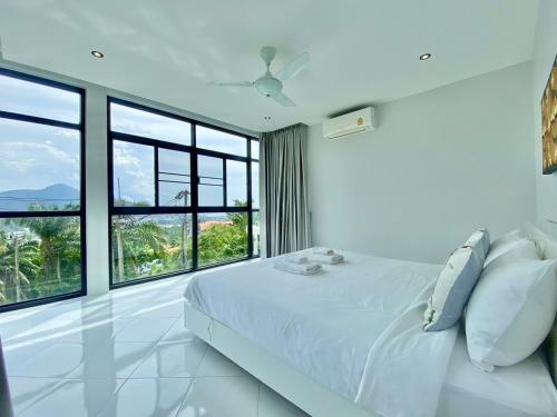 ein weißes Schlafzimmer mit einem Bett und großen Fenstern in der Unterkunft 360 Degree Kamala Seaview Villa in Kamala Beach