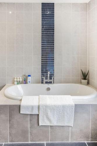 a white bath tub in a white tiled bathroom at The Lookout, Seaside Getaway in Cleveleys