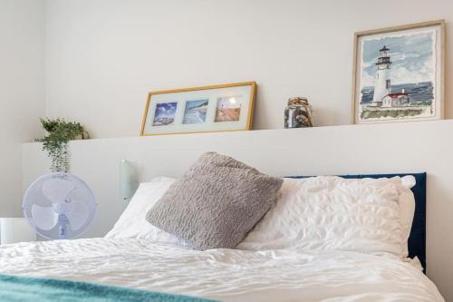 a white bed with a pillow and pictures on the wall at The Lookout, Seaside Getaway in Cleveleys