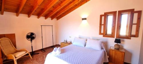 a bedroom with a bed and a chair and a window at Casa con Piscina Privada - By Aloha Palma in Calabardina