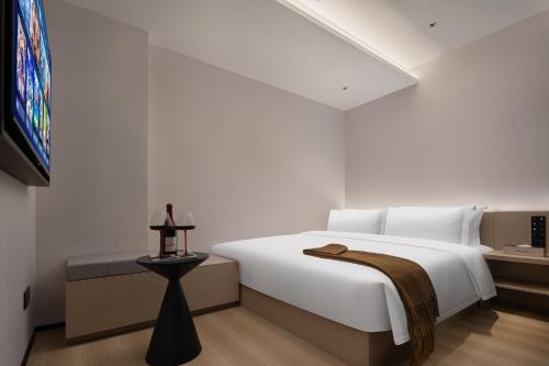 a bedroom with a large white bed and a tv at Guanran Hotel - Yongningmen Subway Station in Xi'an