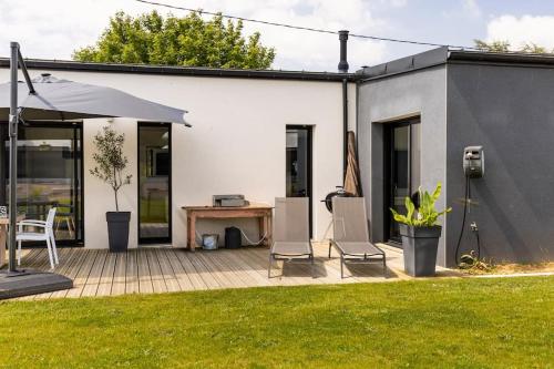 a patio with chairs and an umbrella and a table at Maison à 5 minutes des plages in Lantic