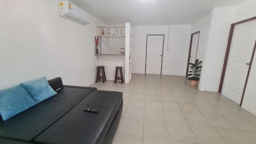 a living room with a black couch and two stools at Koh Mak Garden View for Family&Friends in Ko Mak