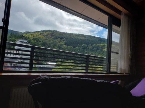 a bedroom with a large window with a view of a mountain at 蔵王温泉 岩清水料理の宿 季の里 in Zao Onsen