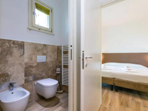 a bathroom with a sink and a toilet and a bed at Toscana Biovillage - Private Cottage in Cecina