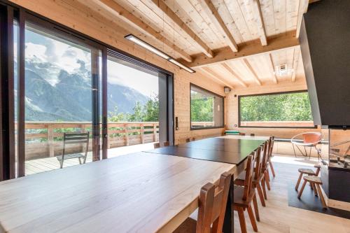Cette chambre dispose de grandes fenêtres et d'une grande table en bois. dans l'établissement Chalet Soljanel, à Chamonix-Mont-Blanc