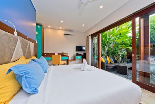 a bedroom with a large bed with blue and yellow pillows at Villa True Colors in Legian
