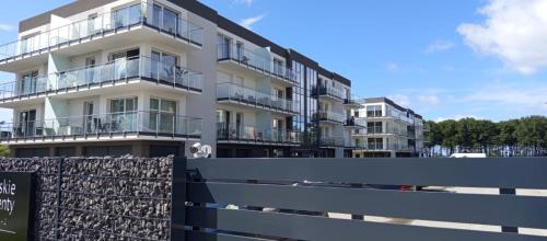 ein Gebäude mit Balkonen und einem Zaun davor in der Unterkunft Apartament przy plaży in Gąski