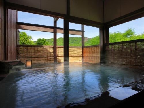 a large pool of water in a room with windows at 蔵王温泉 岩清水料理の宿 季の里 in Zao Onsen