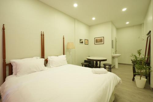 a bedroom with a large white bed and a table at CASA Yaowarat Road ถนนเยาวราช in Samphanthawong