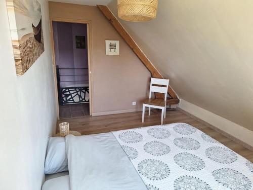 a bedroom with a bed and a chair and a staircase at chez jules, l'entrée des caps in Bazinghen