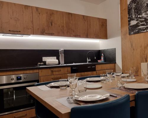 une cuisine avec une table avec des assiettes et des verres à vin dans l'établissement Appartement St Lary - 2 à 6 pers - place du telephérique, plein centre - label 5 diamants, à Saint-Lary-Soulan