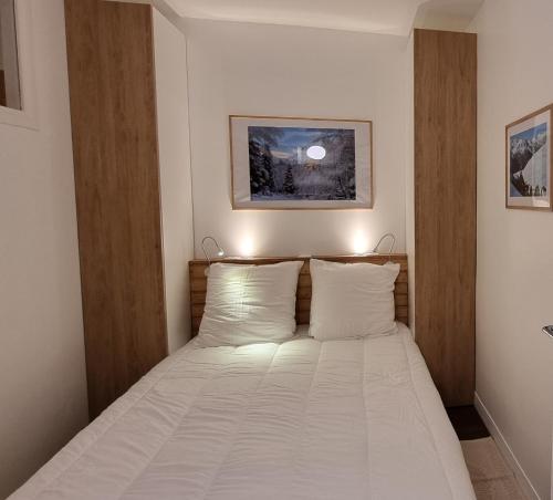 - une chambre dotée d'un lit avec des draps blancs dans l'établissement Appartement St Lary - 2 à 6 pers - place du telephérique, plein centre - label 5 diamants, à Saint-Lary-Soulan