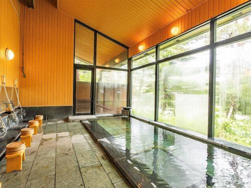 a swimming pool in a room with glass walls at 蔵王温泉 岩清水料理の宿 季の里 in Zao Onsen