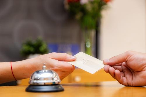 a person holding a piece of paper next to a bell at Hotel Brod - Free Parking in Sofia