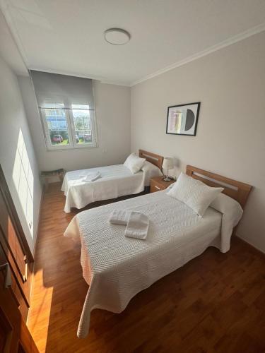 a hotel room with two beds and two windows at Chalet Abelleira Playa Barreiros in Barreiros