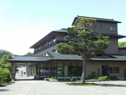 a building with a tree in front of it at 蔵王温泉 岩清水料理の宿 季の里 in Zao Onsen