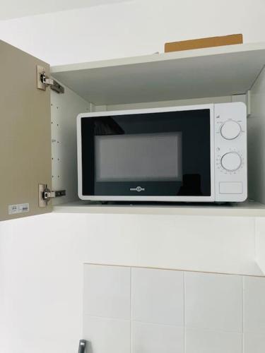 un micro-ondes posé sur une étagère dans une cuisine dans l'établissement STADE DE FRANCE Superbe Appartement Proche Paris, à Saint-Denis