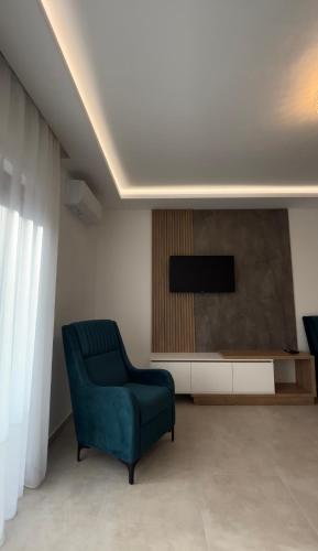 a living room with a blue chair and a television at Apartmani Milos - Meljine in Herceg-Novi