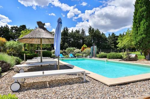 - une piscine avec un parasol, deux chaises, une table et un parasol dans l'établissement Villa La Ponselière-Calme en campagne Provençale, à Graveson
