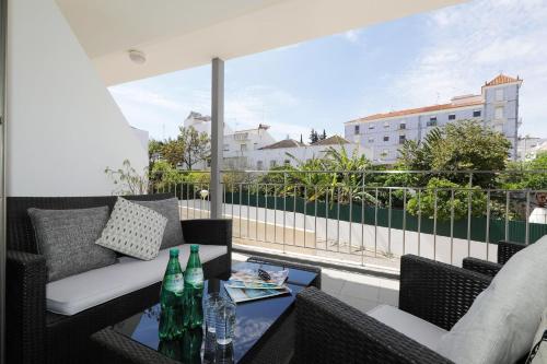 a balcony with chairs and a table with bottles on it at Apt Mossbrae-tavira Centre, Terrasse Et Piscine in Tavira