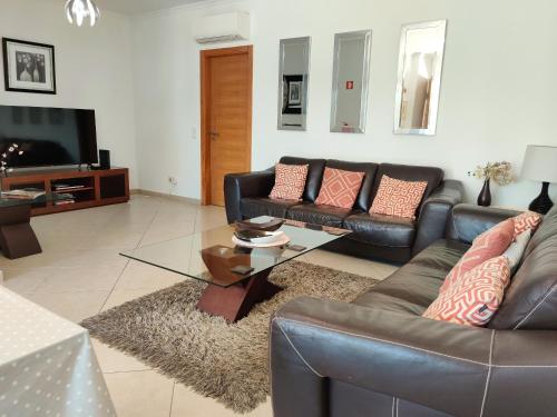 a living room with leather couches and a television at Apt Mossbrae-tavira Centre, Terrasse Et Piscine in Tavira