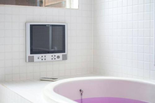 a white bathroom with a tub and a tv at イングリッシュコテージ メイハウス in Oshino