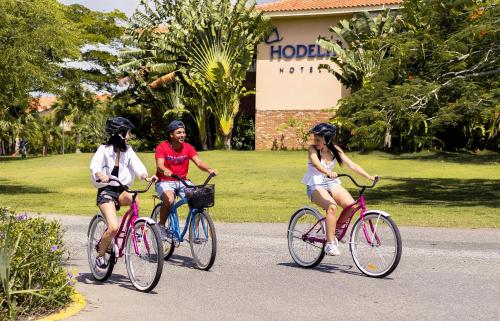 three people riding bikes down a road at Hodelpa Garden Suites - All Inclusive in Juan Dolio