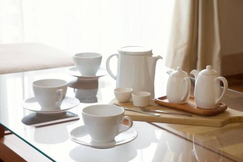 a table with white cups and saucers on it at イングリッシュコテージ メイハウス in Oshino