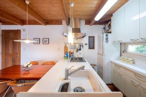 a kitchen with a sink and a wooden table at イングリッシュコテージ メイハウス in Oshino