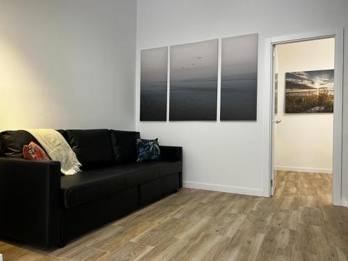 a living room with a black couch and some pictures at Rodrigues 15 in Valencia
