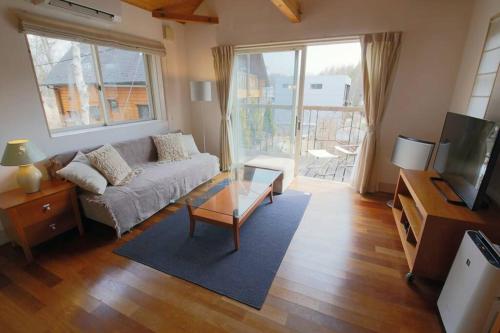 a living room with a couch and a tv at イングリッシュコテージ メイハウス in Oshino