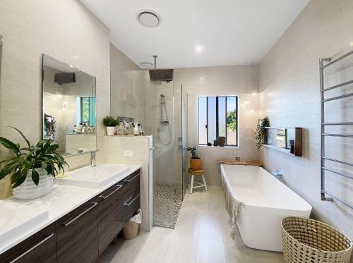 a bathroom with a tub and two sinks and a bath tub at Family Entertainer with Pool - Luxury Holiday House in Lennox Head in Lennox Head