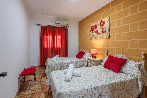 a room with two beds and a red window at Casa Rural Casita de la Cantera in La Lantejuela
