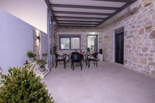 a patio with a table and chairs and a brick wall at Mirabilia Family House in Pitsidia