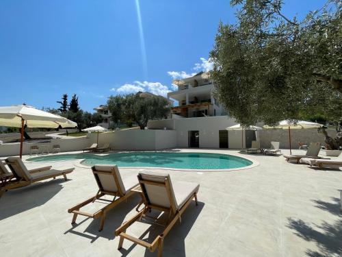 a swimming pool with lounge chairs and a building at Serenity Hill in Paliouri