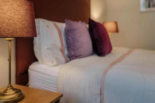 a bedroom with a bed with pillows and a lamp at Killiane Castle Country House & Farm in Wexford