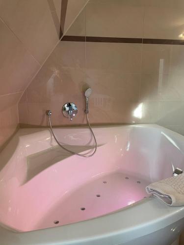 a pink bath tub with a faucet in a bathroom at Strandhaus Deichvoigt in Cuxhaven