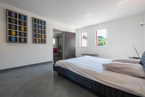 een witte slaapkamer met een bed en twee ramen bij 30VENTSB Villa Eole in Saint-Ambroix