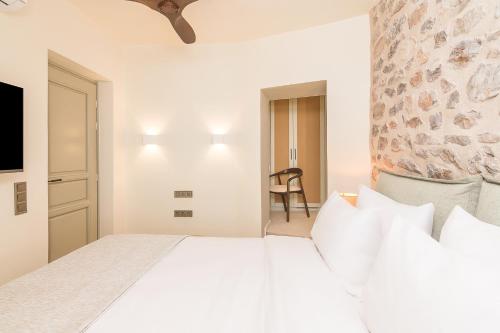 a bedroom with a white bed and a chair at Maison Muse in Hydra
