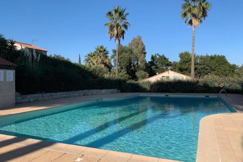 une piscine dans une cour avec des palmiers dans l'établissement Petite maison dans résidence avec piscine, à Cogolin