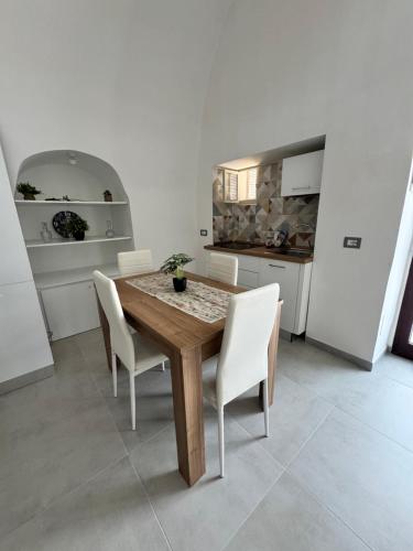 a kitchen with a wooden table and white chairs at Borgo Antico Home in Poggiorsini